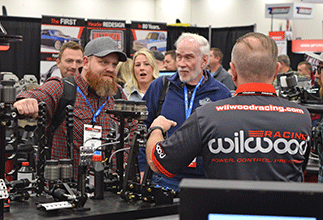 PRI Show attendees talking with exhibitor at booth.